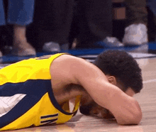 a basketball player laying on the floor with his head in his hands