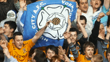 a group of people holding a blue flag that says york city afc on it