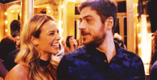a man and a woman are smiling at each other in a crowded room .