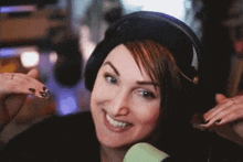 a woman is wearing headphones and smiling in front of a microphone