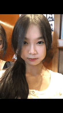 a girl with a ponytail looks at the camera while another girl stands behind her