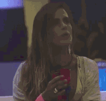 a woman in a gold top is holding a cup of orange liquid