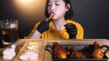 a woman wearing black gloves is eating a piece of pizza