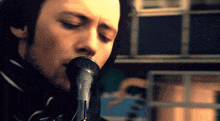 a close up of a man singing into a microphone with his eyes closed