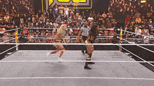 two women are wrestling in a ring with a referee