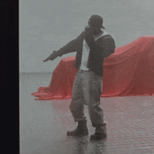 a man with a gun standing in front of a red cloth