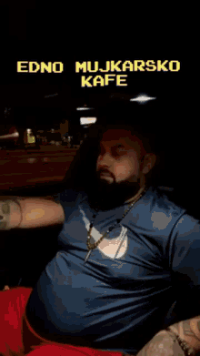 a man with a beard is sitting in a car with the words edno mujkarsko kafe below him