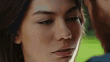 a close up of a woman 's face with a man 's hand on her forehead .