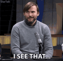 a man sitting in front of a microphone says " i see that ... "