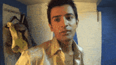 a man in a yellow shirt is standing in a room with clothes hanging on hooks