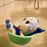a stuffed animal is laying in a bathtub with the letters b3 above it .