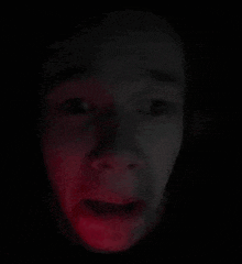 a close up of a person 's face with a red light behind it .