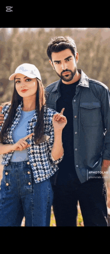 a man and a woman are posing for a picture and the woman is pointing at the camera .