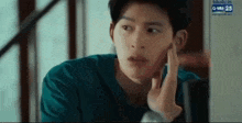 a young man is looking at his face in front of a computer screen .