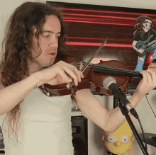 a man playing a violin in front of a microphone