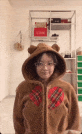 a girl wearing a brown bear hoodie with a plaid heart on the chest