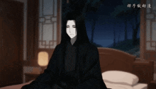 a man with long black hair is sitting on a bed in a dark room
