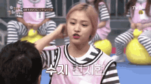 a girl in a pink and black striped shirt is touching a man 's head