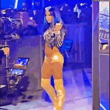 a woman in a yellow outfit is standing on a stage in front of a crowd .