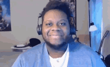 a man wearing headphones and a microphone is smiling while looking at the camera .