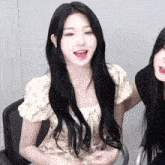 a woman with long black hair is sitting next to another woman with long black hair