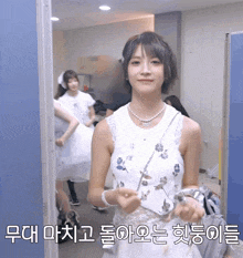 a woman in a white dress stands in front of a blue wall with korean writing