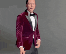 a man in a red tuxedo and bow tie is holding a sword
