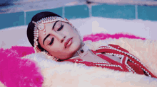 a woman in a red dress is laying on a pink blanket with her eyes closed