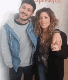 a man and woman are posing for a picture in front of a wall that says inspire you