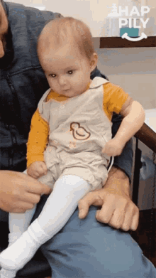 a baby is sitting on a man 's lap and looking up at the camera .