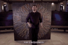 a man standing in front of a painting that says yay crossings on it