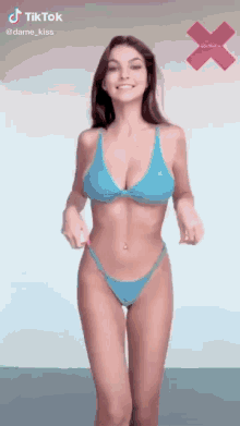 a woman in a blue bikini is standing in front of an x on a white background .
