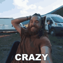 a man with long hair and a beard is taking a selfie with the word crazy written on it