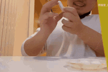 a man with a beard is sitting at a table with chinese writing on a yellow box behind him