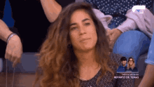 a woman sitting in front of a sign that says hoy a las 19:00
