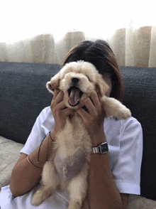 a woman wearing a watch is holding a small dog