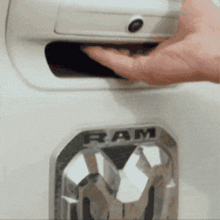 a person 's hand is reaching into a ram emblem