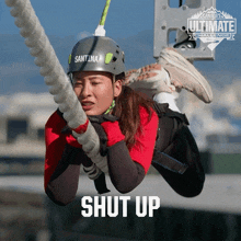 a woman wearing a helmet that says santina on it is hanging from a rope