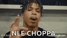 a man with dreadlocks is making a funny face and says `` nle choppa '' with his hand .