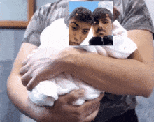 a man is holding a baby in his arms with a picture of two men in the background