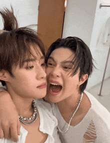 two young men are making funny faces and one is wearing a necklace with pearls