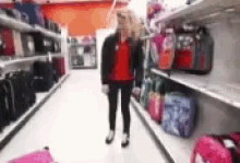 a woman is standing in the middle of a store aisle .