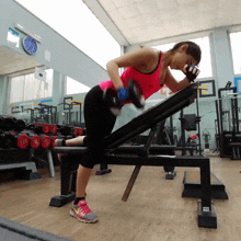 a woman is lifting a dumbbell in a gym