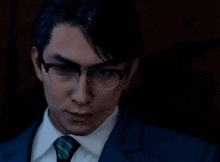 a man wearing glasses and a suit looks at the camera