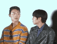 two men are standing next to each other and looking at each other .
