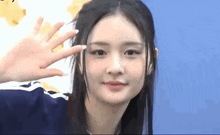 a woman with long black hair is waving her hand