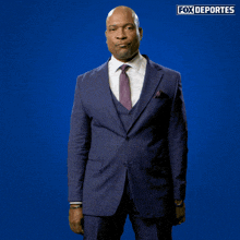a man in a suit and tie is standing in front of a fox deportes sign