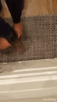 a person is tying their shoelaces on a rug ..