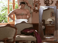 a shirtless man is standing in front of a large mirror