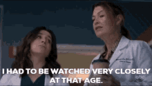 two women in white coats are standing next to each other and talking .
